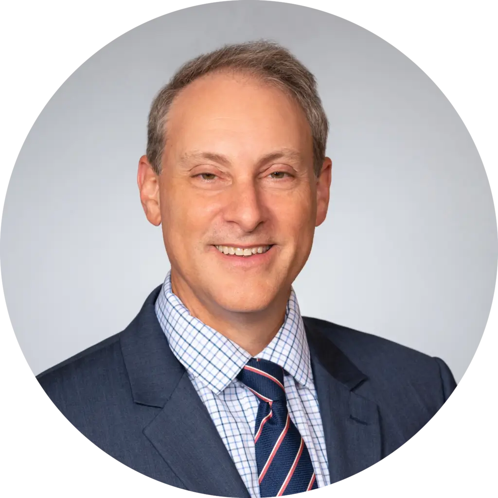 Professional man in a business suit smiling against a neutral background.